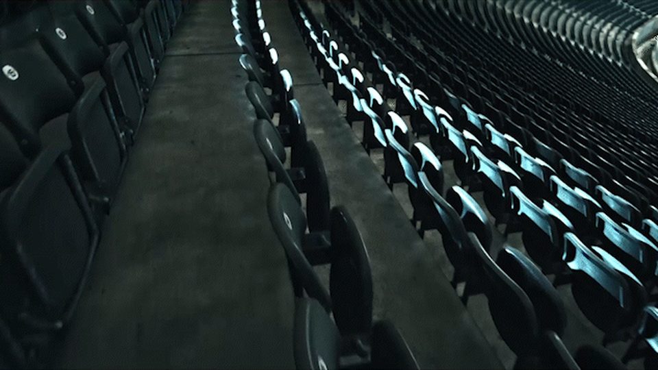 Empty stadium seats in raking rows with cold light coming up the seat backs